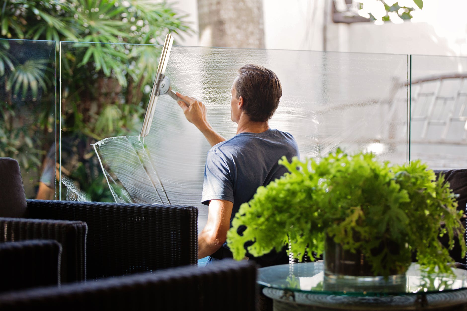 man in gray shirt cleaning clear glass wall near sofa